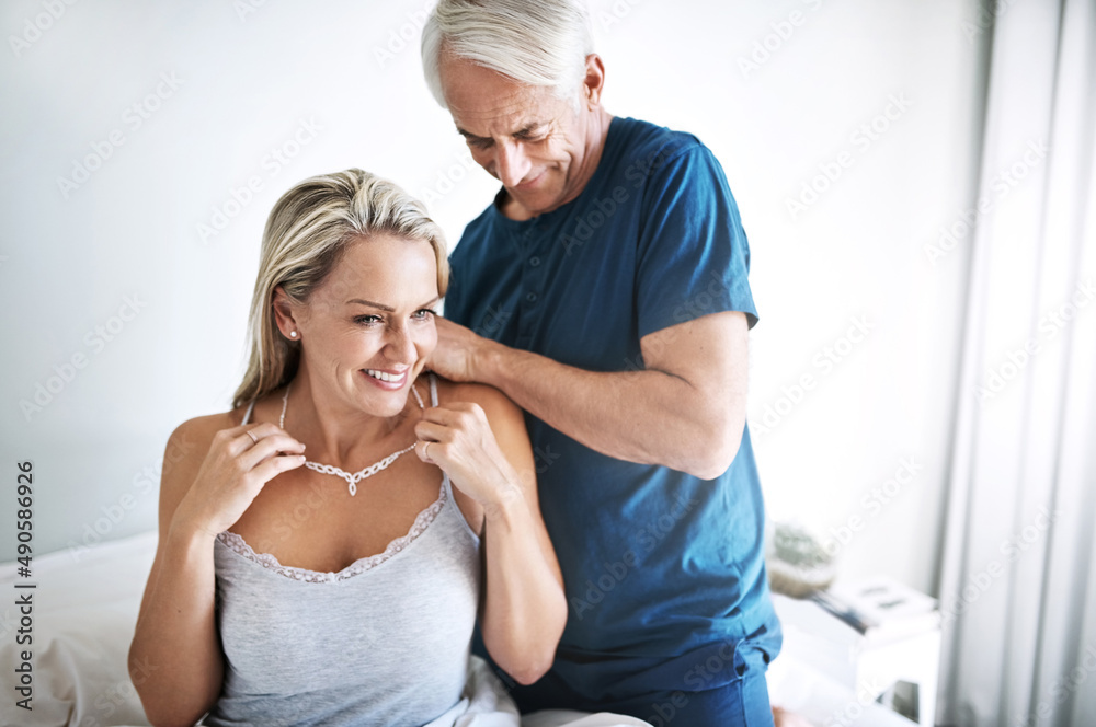 Fototapeta premium You know just how to spoil me. Shot of a mature man putting a necklace around his wifes neck at home.