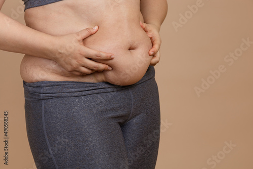 Front view of hands squeezing extra weight big belly of lady in