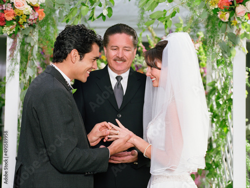 Groom slipping the ring on his bride's finger photo