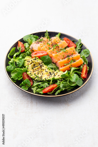 Salmon fish fillet with fresh salad, avocado top view.