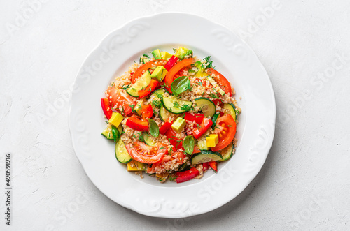 Vegetarian salad with quinoa, avocado, cucumber and sweet pepper on a gray background.