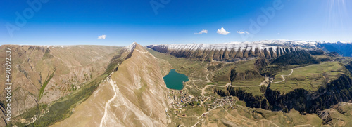 Lake Mochokh in the Republic of Dagestan, Russia. Snow-capped peaks top mountains in sunny weather. Gorge and ridges Kachta Ochlinski and Tanusdiril. Highlands. Vertical panorama. Travel in Dagestan.
