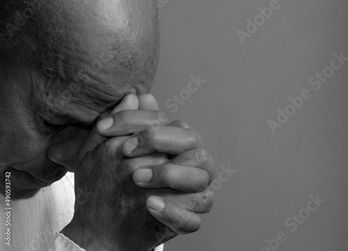 man praying to god with hands together on dark background stock photo