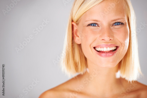 She will bring all the attention here - Copyspace. Portrait of a pretty young woman with a large grin and copyspace beside her.