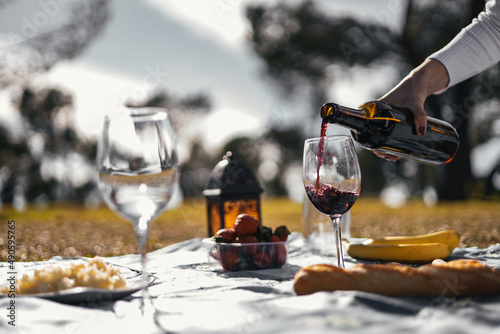 unrecognizable woman filling wine glass in a picnic