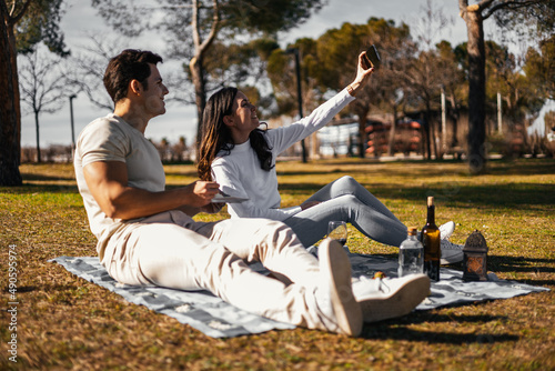 Fototapeta Naklejka Na Ścianę i Meble -  couple in picnic, she is taking a selfie to remember the moment in the future