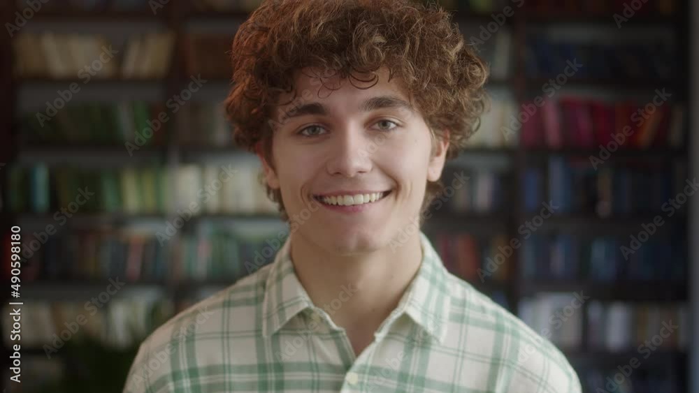 Portrait of Attractive Man Student Standing in Front of the Camera and Laughing in High School Library. Education, Literature and People Concept. Portrait of Attractive Man Student Standing in Front of the Camera and Laughing in High School Library. Education, Literature and People Concept.