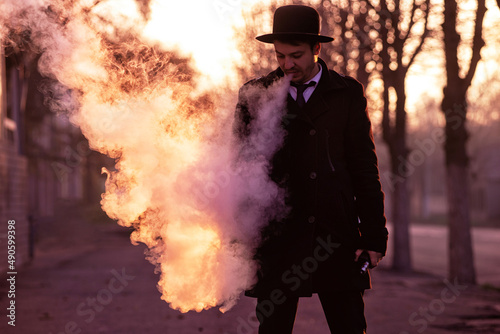 Portrait of handsome man in black hat smoking electronic cigarette in on city street.