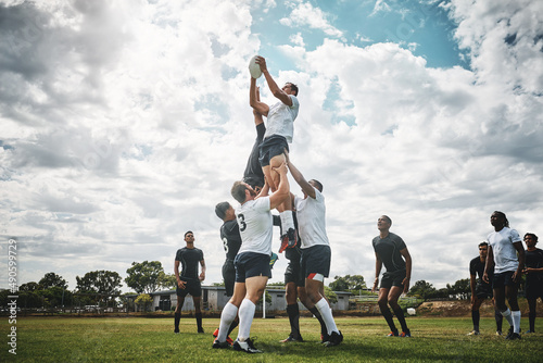 Reach for the sky. Shot of two rugby teams competing over a ball during a line out of a rugby match outside on a filed. photo