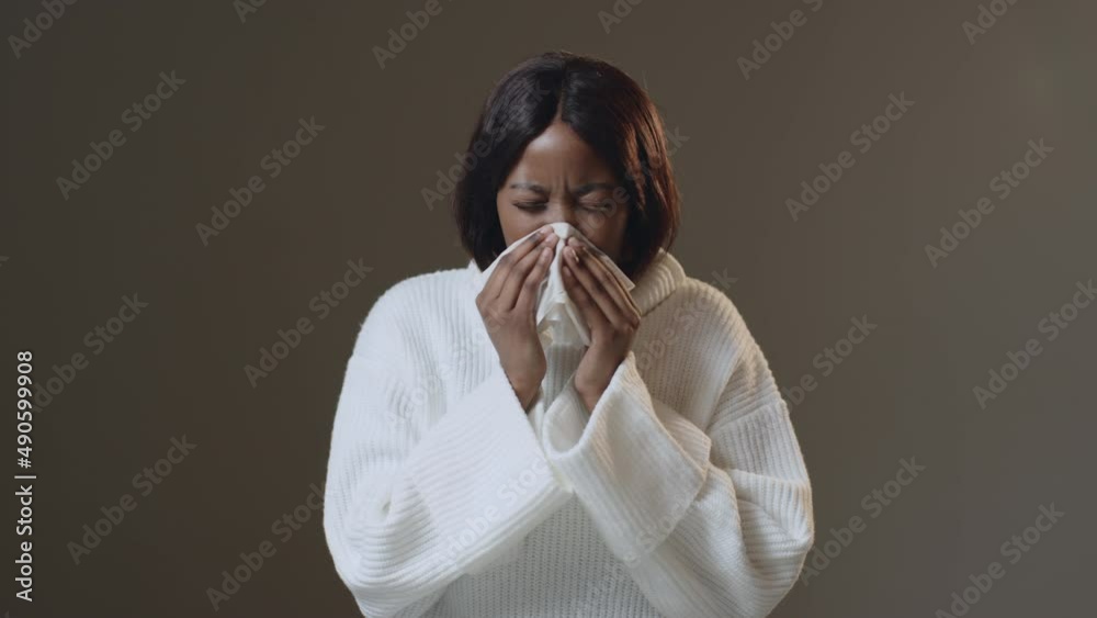 Ill young african american woman sneezing in tissue, suffering seasonal allergy or flu, influenza. ProRes codec Ill young african american woman sneezing in tissue, suffering seasonal allergy or flu, influenza. ProRes codec