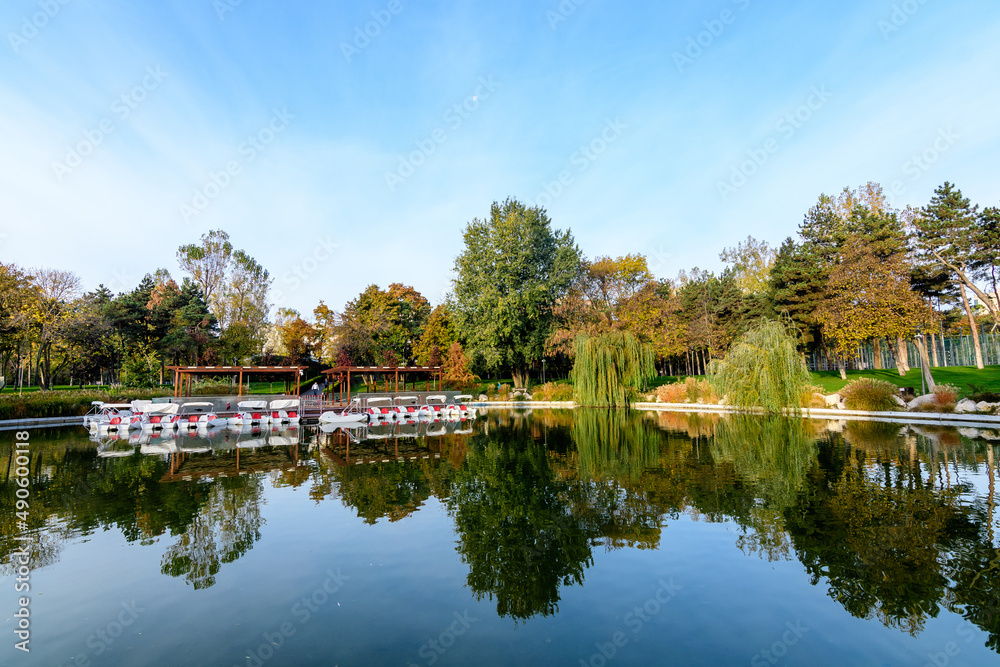Landscape with the lake and green and yellow trees in Drumul Taberei Park, also known as Moghioros Park, in Bucharest, Romania, at sunrise in an autumn morning. Landscape with the lake and green and yellow trees in Drumul Taberei Park, also known as Moghioros Park, in Bucharest, Romania, at sunrise in an autumn morning.