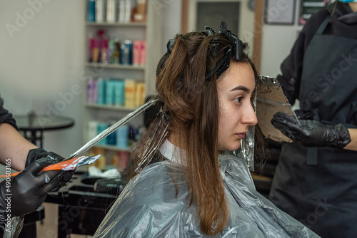 super cool stylist working on the image of a young girl in a beauty salon. © RomanR