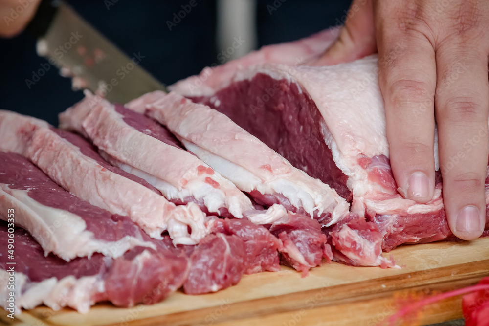 Cutting beef on the table with sharp knife with landscape background.