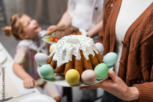 Wall Mural senior woman holding easter cake near family during easter celebration