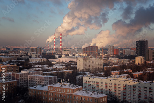 View of the big city from above. Smoking chimneys of boiler rooms on the background of the cityscape