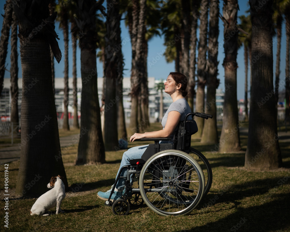 Caucasian woman in wheelchair with dog under palm trees. Caucasian woman in wheelchair with dog under palm trees.