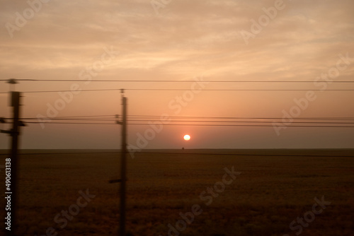 View from the train window. Sunrise in the steppe. Railway poles. © Anna