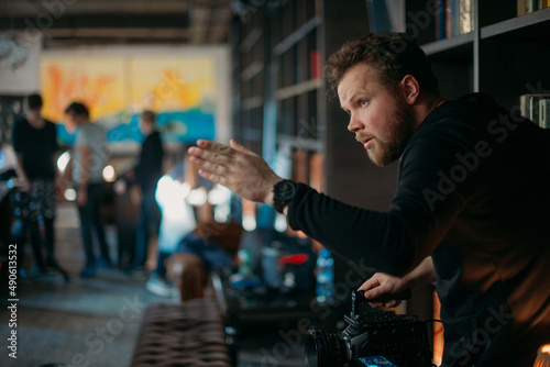 Director of photography with a camera in his hands on the set. Professional videographer at work on filming a movie, commercial or TV series.