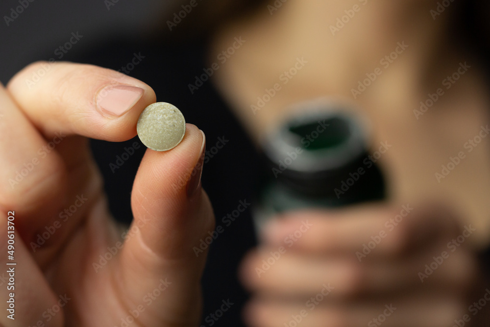 Closeup of a woman holding an iodine pill.