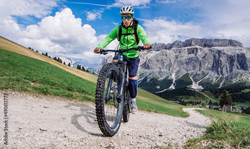 Rower górski, vhłopak jedzie rowerem elektrycznym ścieżką w górach w Dolomitach .