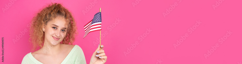 A young happy girl with a smile on her face holds an American flag in her hands. Symbol of patriotism and freedom. A young happy girl with a smile on her face holds an American flag in her hands. Symbol of patriotism and freedom.