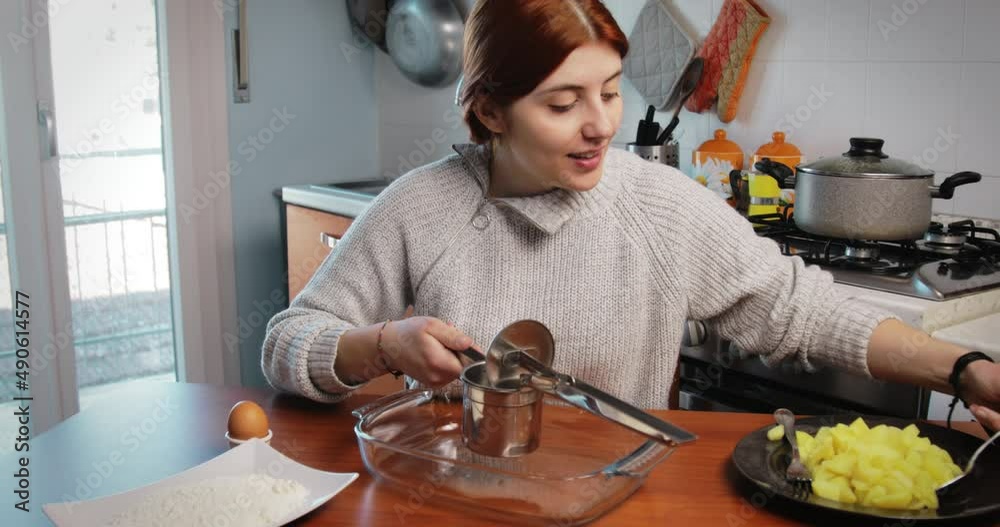 Girl is mashing boiled potatoes for the preparation of dumplings and croquettes Girl is mashing boiled potatoes for the preparation of dumplings and croquettes