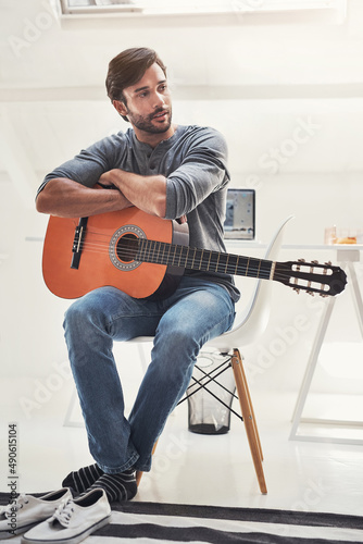 No music, no life. Know music, know life. Shot of a handsome young man practising guitar at home.