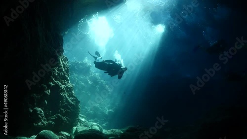 cave diving underwater scuba divers exploring caves and having fun ocean scenery sun beams and rays background photo