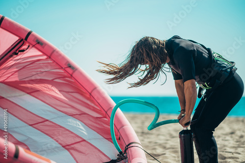 Woman preparing kiteboarding kite with the air pump photo