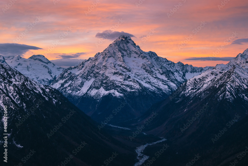 Fantastic view of a high snow-capped mountain at sunset