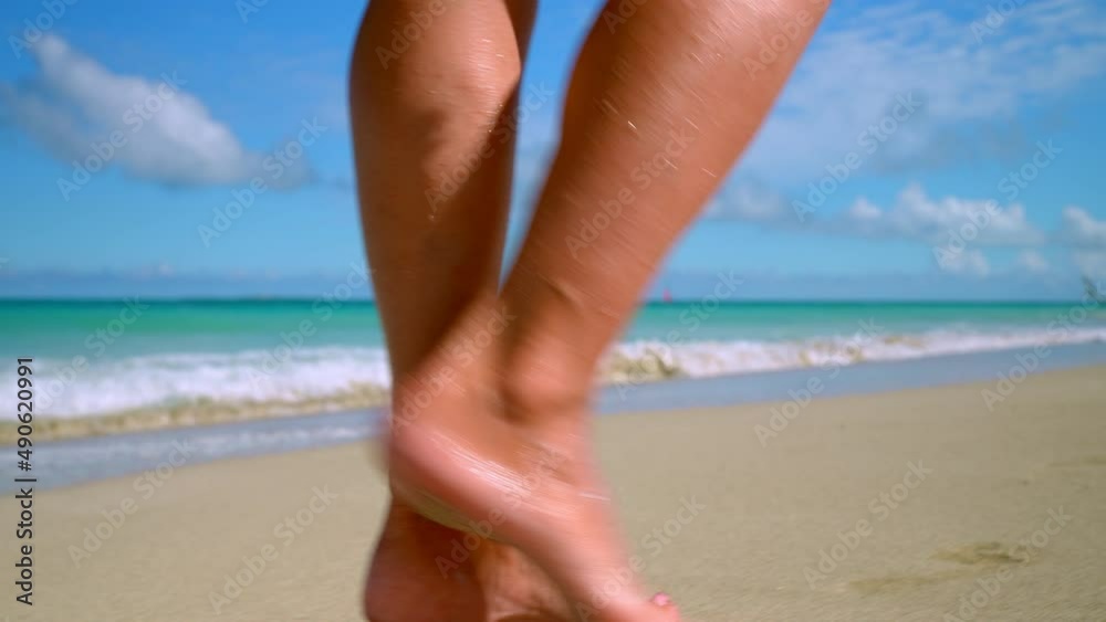 women's feet walk along the sandy beach to the shore of the blue sea. women's feet walk along the sandy beach to the shore of the blue sea.