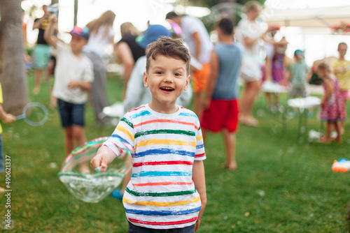 emotional child with soap bubbles. An emotional boy with a big bubble. Summer weekend, recreation, children's animation in the park in the fresh air, animation program with soap bubbles.
