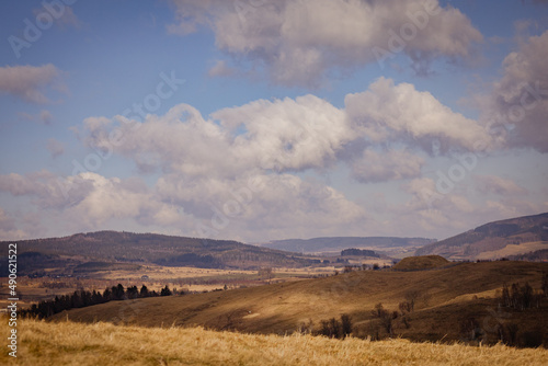 Rural landscape with haystacks and blue cloudy sky. Bright yellow fields