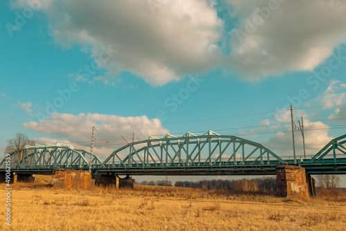 Blue railway bridge over the river Oder, Scinawa, Poland. Bright cloudy sky industrial landscape.