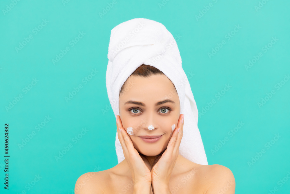 smiling young woman applying face cream on blue background smiling young woman applying face cream on blue background