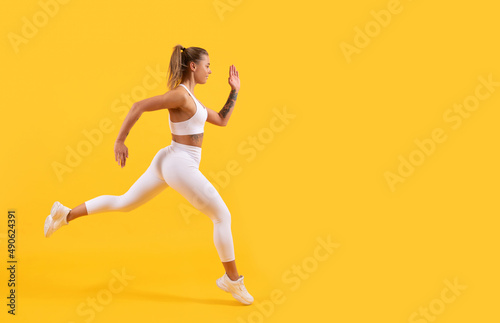 sport girl runner running on yellow background. copy space