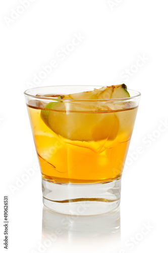 Glass of yellow alcohol cocktail with ice and slice of apple on white background
