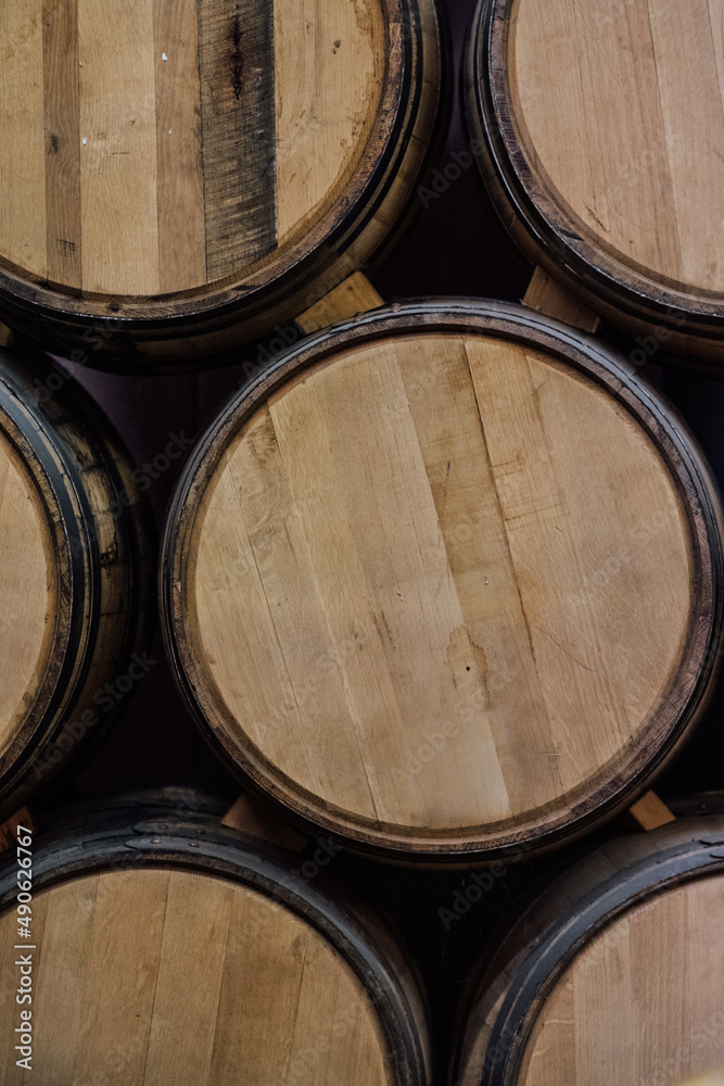 unlabeled American oak whiskey barrels stacked on each other using wooden wedge in distillery rackhouse warehouse