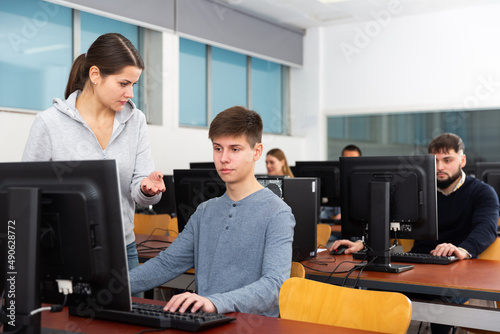 Female teacher helping young male student in computer class in university. High quality photo