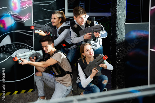 Smiling young friends playing laser tag game with colored laser. High quality photo