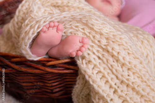 newborn's legs covered with a knitted blanket of milky color