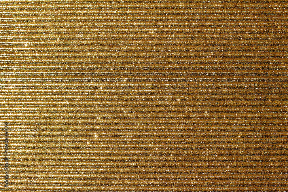 Full frame macro abstract texture background of shimmering golden glitter corrugated surface