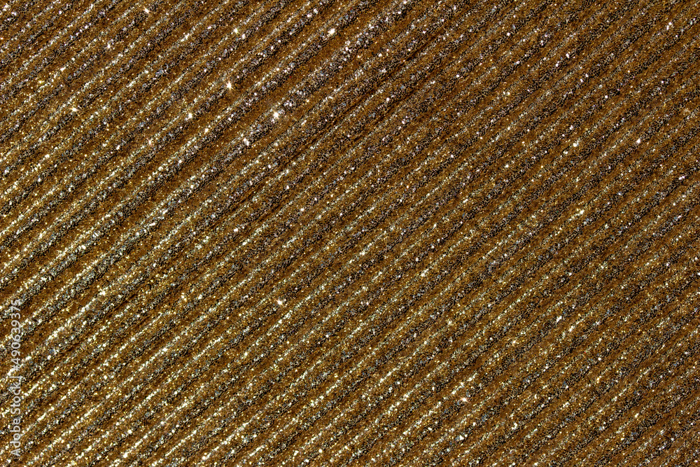 Full frame macro abstract texture background of shimmering golden glitter corrugated surface
