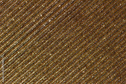 Full frame macro abstract texture background of shimmering golden glitter corrugated surface