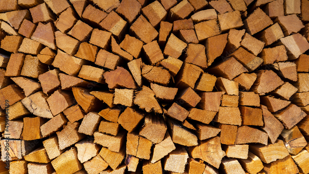 Firewood cut and stacked. Wall of wooden pieces. Warm colors with shades of brown. Wood stacked with precision. Wooden natural cut logs texture background Firewood cut and stacked. Wall of wooden pieces. Warm colors with shades of brown. Wood stacked with precision. Wooden natural cut logs texture background