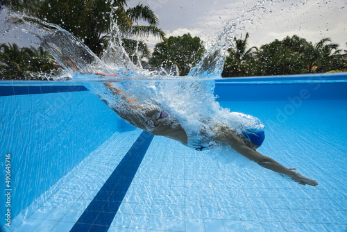 Portrait of a female swimmer, that jumping and diving into swimming pool. Sporty woman.Low angle view from the swimming pool.