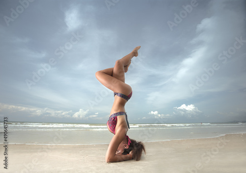 Young woman practicing yoga on the beach