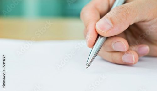 Hand with pen signing on paper