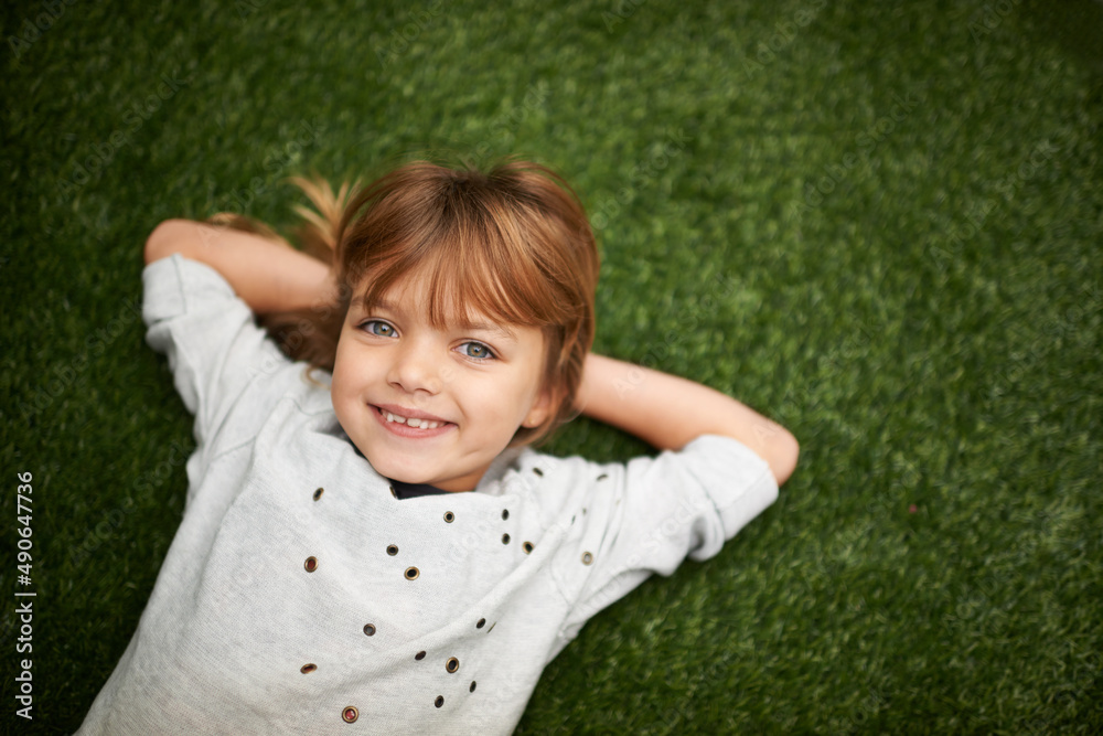 Shes a charmer. Little girl lying on the grass with her hands behind her head. Shes a charmer. Little girl lying on the grass with her hands behind her head.
