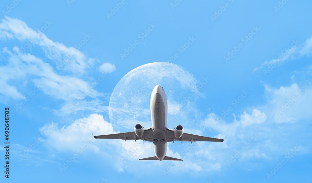 Fototapeta premium White passenger airplane in the clouds with full moon - Travel by air transport